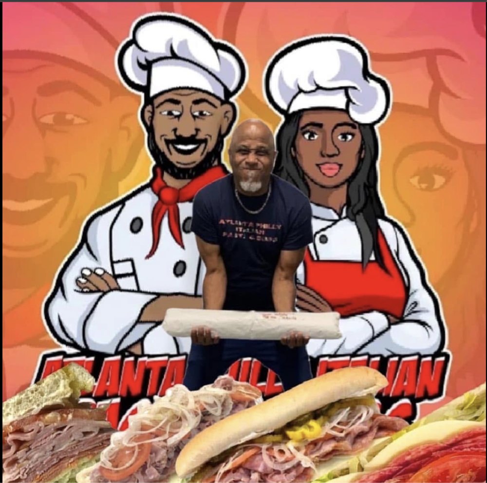 Owner holding a fresh sub in front of the Atlanta Philly Italian mascot artwork